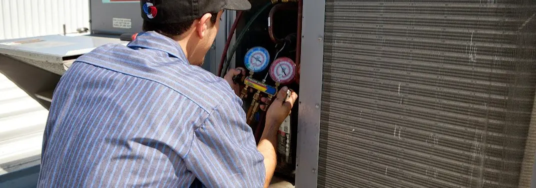HVAC technician servicing a condenser unit in Potomac Mills